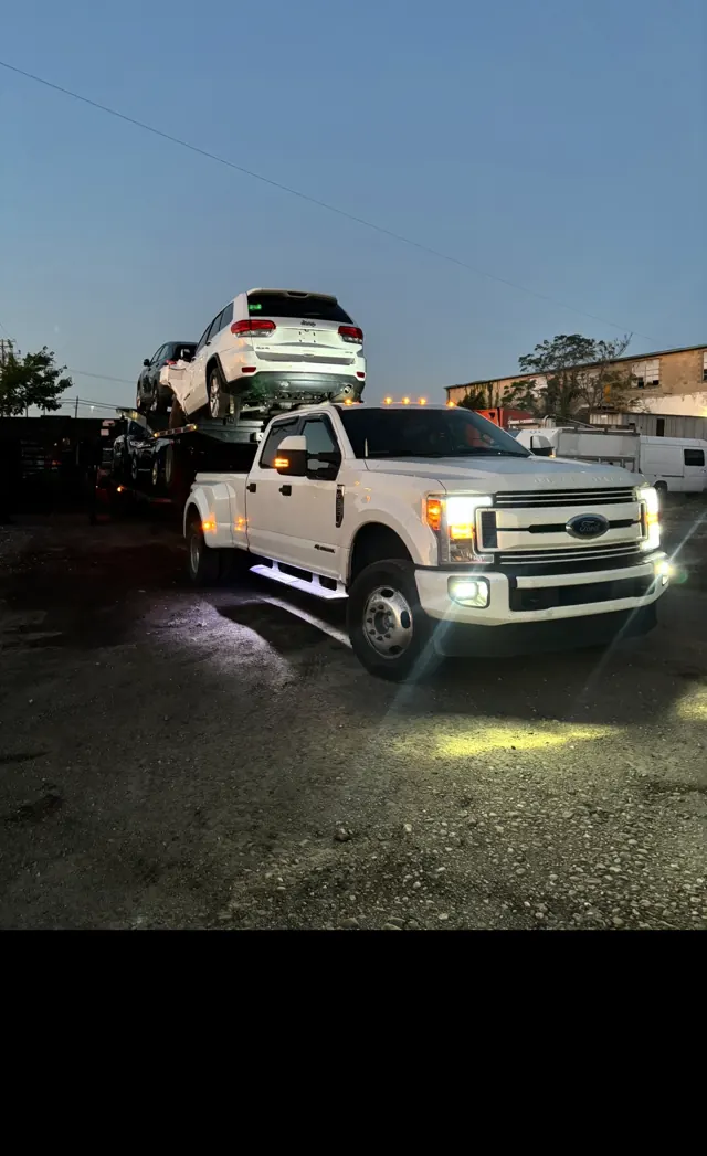 Loaded car hauler in a yard at dusk