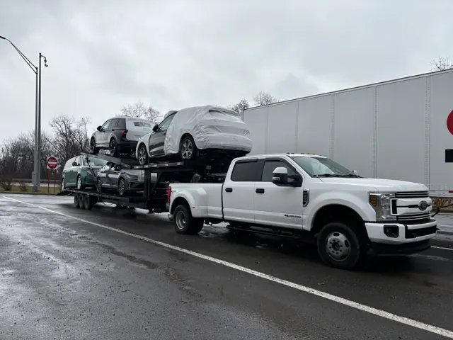 Loaded car hauler on a wet lot under overcast sky